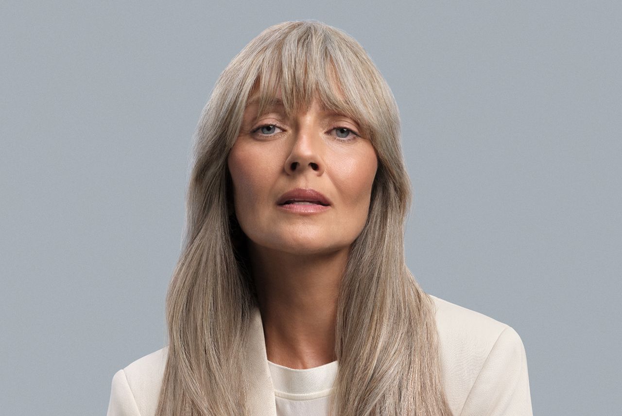 Model with long light hair styled into Birkin bangs.