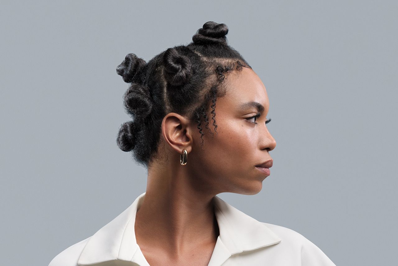 Model with dark coily hair in a Gentle Bantu knotted style.