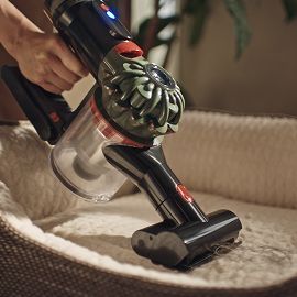 The Dyson V8 Cyclone vacuum is used with the Mini motorised tool to clean a pet bed.