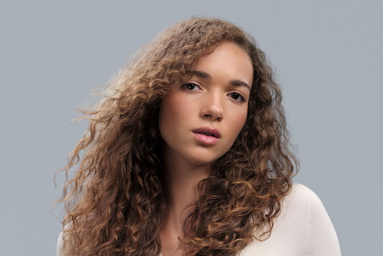 Model with light-brown curly hair styled into Fairy curls.