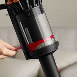A person compressing dirt inside the bin of the Dyson Piston Animal vacuum.