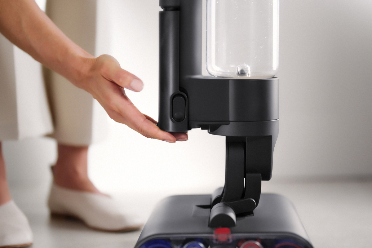 A user touching the Dyson Wash G1 wet cleaner's battery pack.