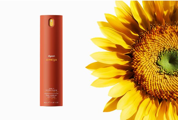 Dyson Omega leave-in conditioning spray next to a sunflower head.