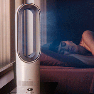 The Dyson Hot+Cool HF1 Remote Link Pre-heat heater and cooling fan operates quietly in a bedroom near a sleeping person.