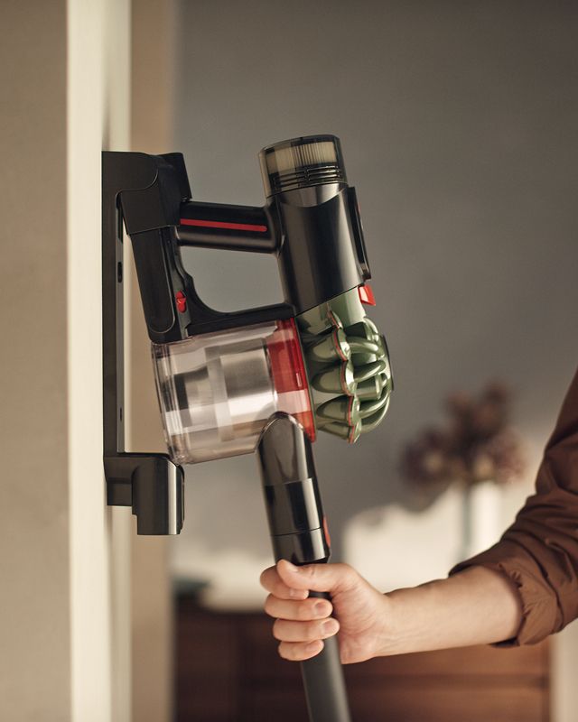 The Dyson V8 Cyclone vacuum is returned to its charging dock.